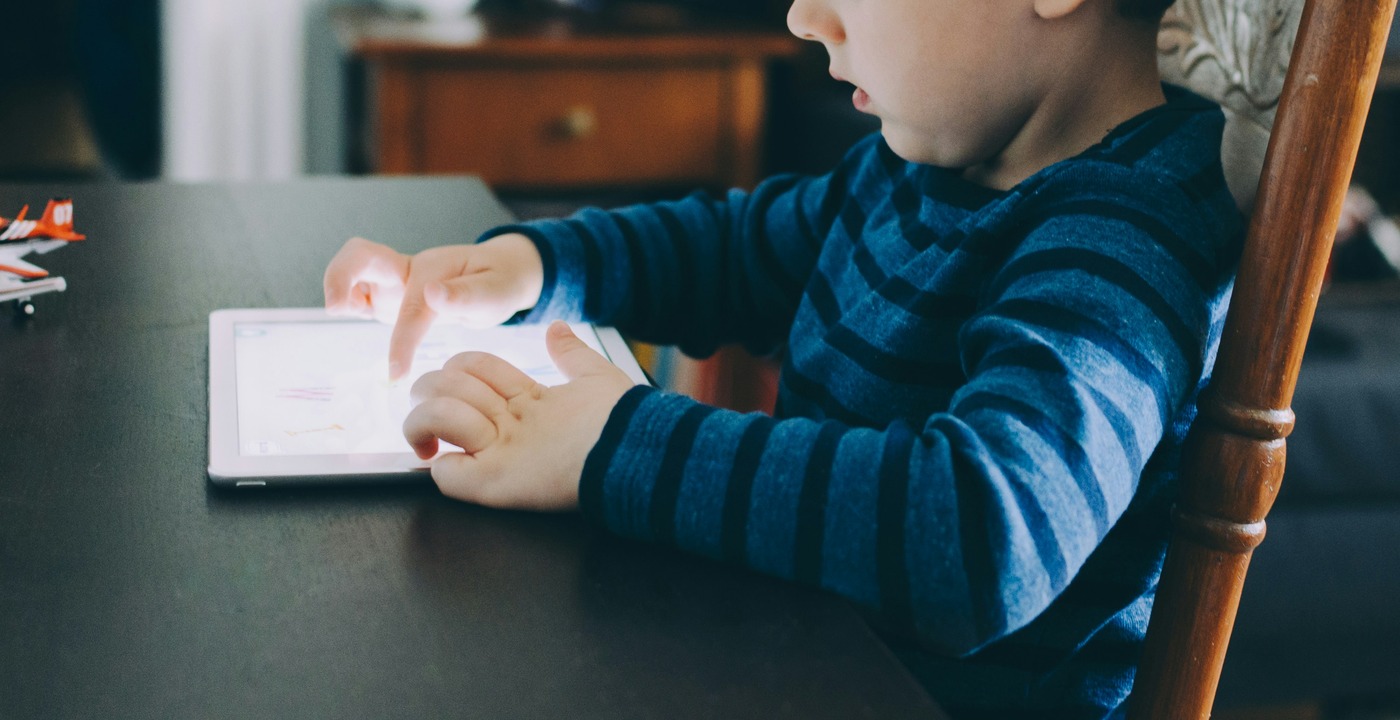 Toddler using a paint by numbers canvas to draw in an ipad.